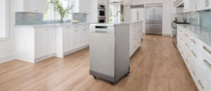 What is a Portable Dishwasher shown in a big bright modern kitchen, featuring a freestanding stainless steel portable dishwasher on wheels placed near a kitchen island.
