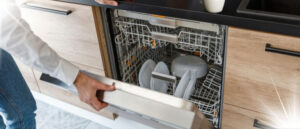 Person checking clean dishes in a dishwasher, illustrating different types of dishwashers.