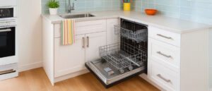 Modern kitchen with an open dishwasher under the sink, colorful accents, and clean interior used to visually debunk common dishwasher myths.