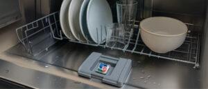 Interior of a dishwasher showing clean wet dishes and a detergent compartment with a Dishwasher Pod Not Dissolving highlighting a common cleaning issue.