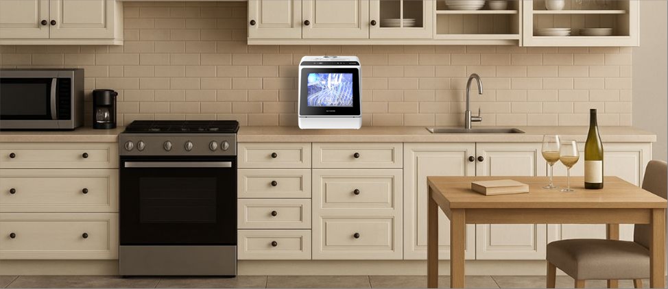 A modern kitchen setup featuring the BLITZHOME BH-CDW1 countertop dishwasher placed neatly on the counter between the stove and sink. Its sleek white body with a glossy black control panel and transparent viewing window blends seamlessly with the cream cabinetry, offering a compact yet stylish dishwashing solution for small kitchens, apartments, and RV spaces.