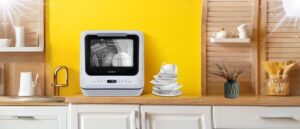 A sleek COMFEE countertop dishwasher on a kitchen counter with clean stacked dishes beside it, exemplifying the best COMFEE Countertop Dishwashers for home use.