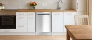 The Honeywell HDS24SS Dishwasher blends seamlessly into a modern white kitchen setup, positioned between the sink and oven with a sleek stainless steel finish. This image, perfect for the Honeywell HDS24SS Dishwasher Review, shows off the appliance’s built-in design and how well it complements clean, minimalist decor with natural wood accents.