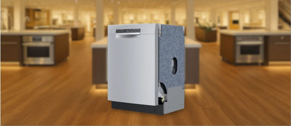 17_BOSCH-SGE53B55UC-dishwasher-review In this BOSCH SGE53B55UC Dishwasher Review image, the built-in (under-counter) dishwasher is displayed in a showroom setting, highlighting its modern design and sleek front panel.