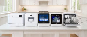 Bright and modern kitchen interior with large windows, showcasing five Best Featured Countertop Dishwashers neatly arranged on the counter, including sleek white and glass-front designs, all organized in a clean and visually appealing display that highlights premium style and functionality.