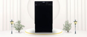 A featured image of the topic Danby DDW1804EB Dishwasher Review. A Danby DDW1804EB dishwasher is showcased on a pedestal with a glowing halo at the base, flanked by ornamental plants and other things, set against a backdrop of elegant white curtains.
