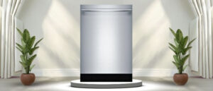 A featured image of the topic Bosch SHX89PW75N Dishwasher Review. A Bosch SHX89PW75N dishwasher is showcased on a pedestal with a glowing halo at the base, flanked by ornamental plants and other things, set against a backdrop of elegant white curtains.
