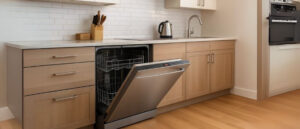 Open stainless steel dishwasher in a modern kitchen with light wood cabinets, illustrating the decision point in asking is a dishwasher right for you.