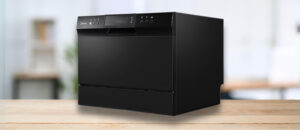 Midea MDC22P1ABB countertop dishwasher in black with a digital display and control buttons, placed on a wooden surface in a modern kitchen setting. The appliance features an Energy Star certification label on the lower right corner. It is featured image of the topic "Midea MDC22P1ABB Dishwasher Review."