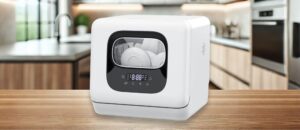 Joy Pebble DW8306 Dishwasher Review: A modern kitchen setup featuring the Joy Pebble DW8306 countertop dishwasher placed on a wooden counter. The image highlights its compact size, sleek white design with a black panel, and digital display, making it a stylish and space-saving appliance.