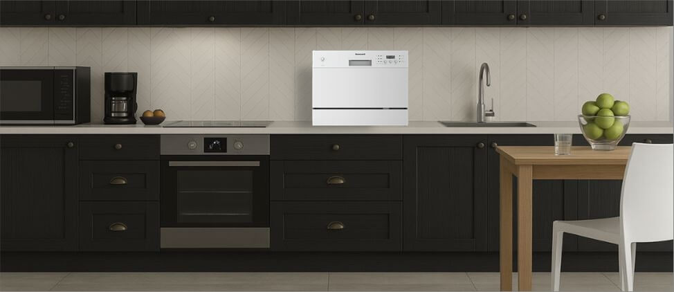 A visual size comparison chart displaying the BLACK + DECKER BCD6SD dishwasher alongside a standard kitchen counter and average human heights. The graphic helps users understand its compact dimensions and how it fits within a regular kitchen environment.