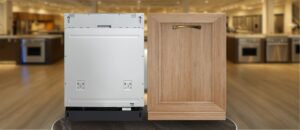 Featured image of KoolMore KM-DW2445-PR Dishwasher Review: This image shows the KoolMore KM-DW2445-PR dishwasher next to a wooden panel door in a showroom-style kitchen environment. The dishwasher is designed for built-in installation and supports a panel-ready finish, allowing it to blend seamlessly into various cabinetry styles for a clean, integrated look.