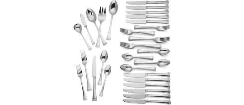 Lenox 815486 Portola flatware set with 65 polished stainless steel utensils, including serving spoons, knives, forks, and teaspoons laid out neatly on a white background.