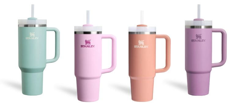 Four Stanley Quencher tumblers in pastel colors—teal, pink, peach, and lavender—each with a built-in handle and straw.