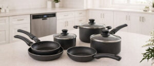 A modern kitchen with bright lighting features a stylish set of the best nonstick cookware sets arranged neatly on a countertop, with a built-in dishwasher visible in the background.