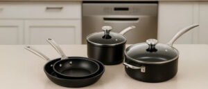 can non stick pans go in the dishwasher shown as a cookware set on kitchen counter with dishwasher in background