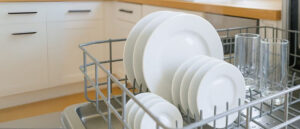 Dishwasher-safe dinnerware neatly arranged in a dishwasher rack, including white plates and clear drinking glasses, showcasing easy and safe cleaning for modern kitchens.