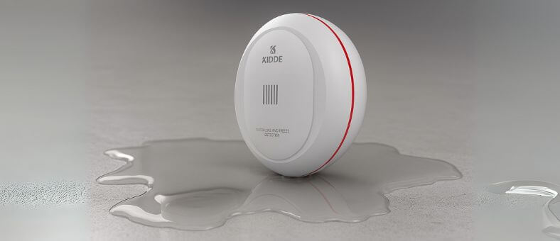 Circular Kidde water leak detector placed on a wet floor, showing active water detection.