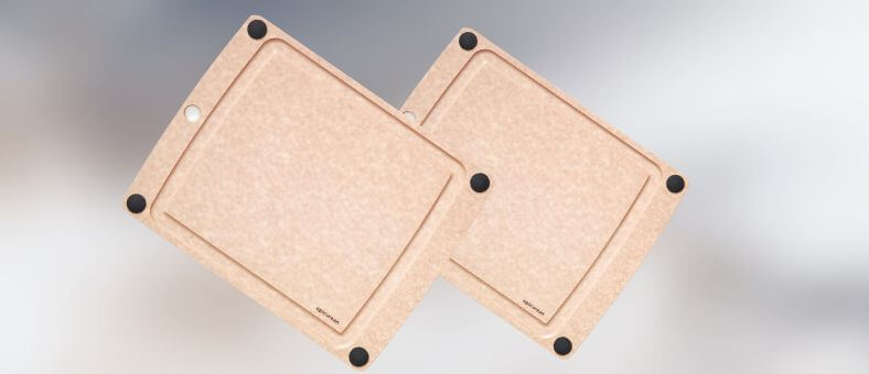 Two eco-friendly composite wood cutting boards with corner grips and juice grooves, displayed on a soft background.