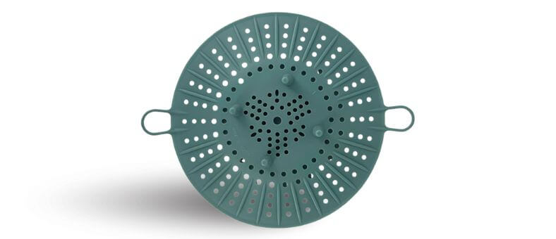 Image features a round green silicone steamer basket viewed from the top, with perforated holes for even steam flow.