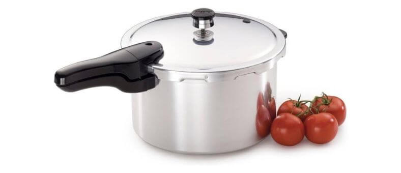 Aluminum pressure cooker with tomatoes beside it