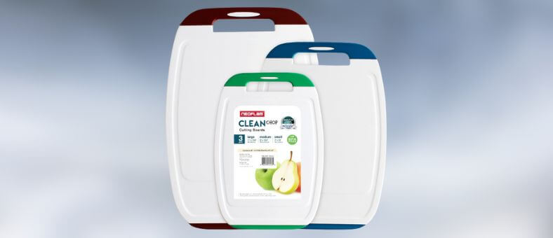A set of three color-coded plastic cutting boards with integrated handles, designed for safe food separation and easy storage.