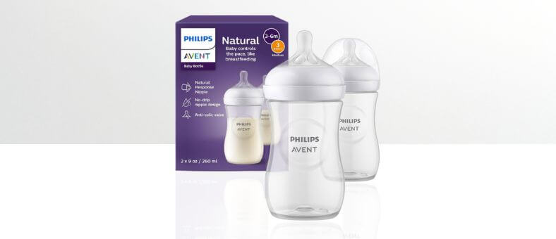 Philips Avent Natural Baby Bottles – Two clear baby bottles with white caps in front of a purple product box on a white background.