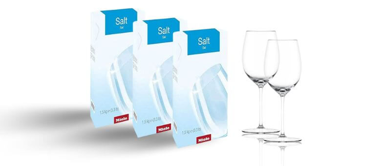 Miele Dishwasher Salt boxes placed beside clear wine glasses, showing brand-specific premium salt for dishwashers.