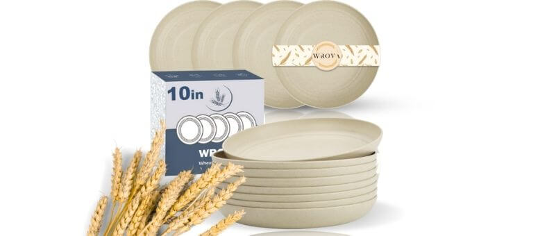32-piece beige dishwasher safe bamboo dinnerware set with plates, bowls, and cups stacked neatly beside wheat stalks.