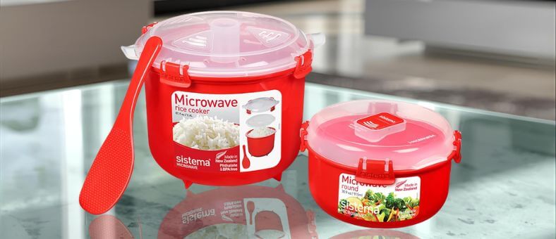 Red Sistema microwave rice cooker with spoon and container on kitchen counter, a compact dishwasher safe rice cooker option.