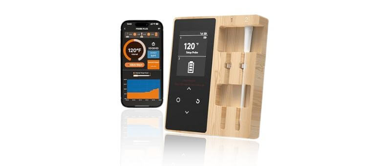 A sleek smart wireless meat thermometer with a wooden charging base and smartphone app display showing temperature and cooking data.
