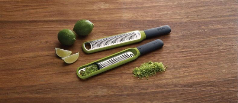Joseph Joseph green zesters with fresh lime zest on a wooden surface.